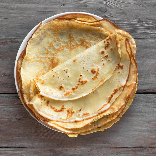 a plate of crepes on a wood table 